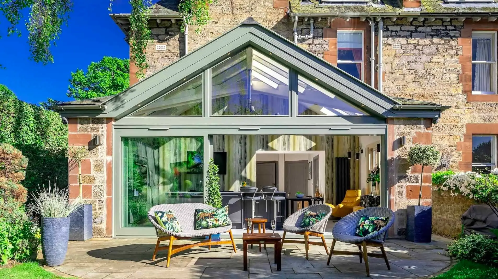 A Mozolowski & Murray glass and timber garden room opening onto a stone patio